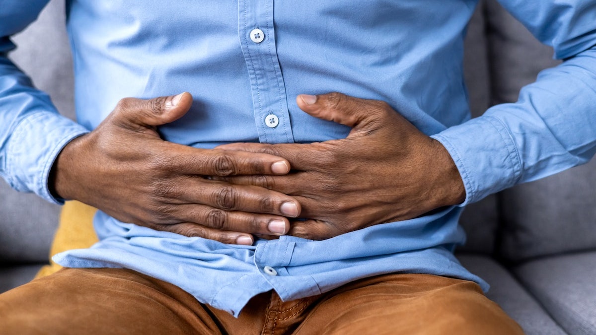 Man holding his stomach while sitting on a couch