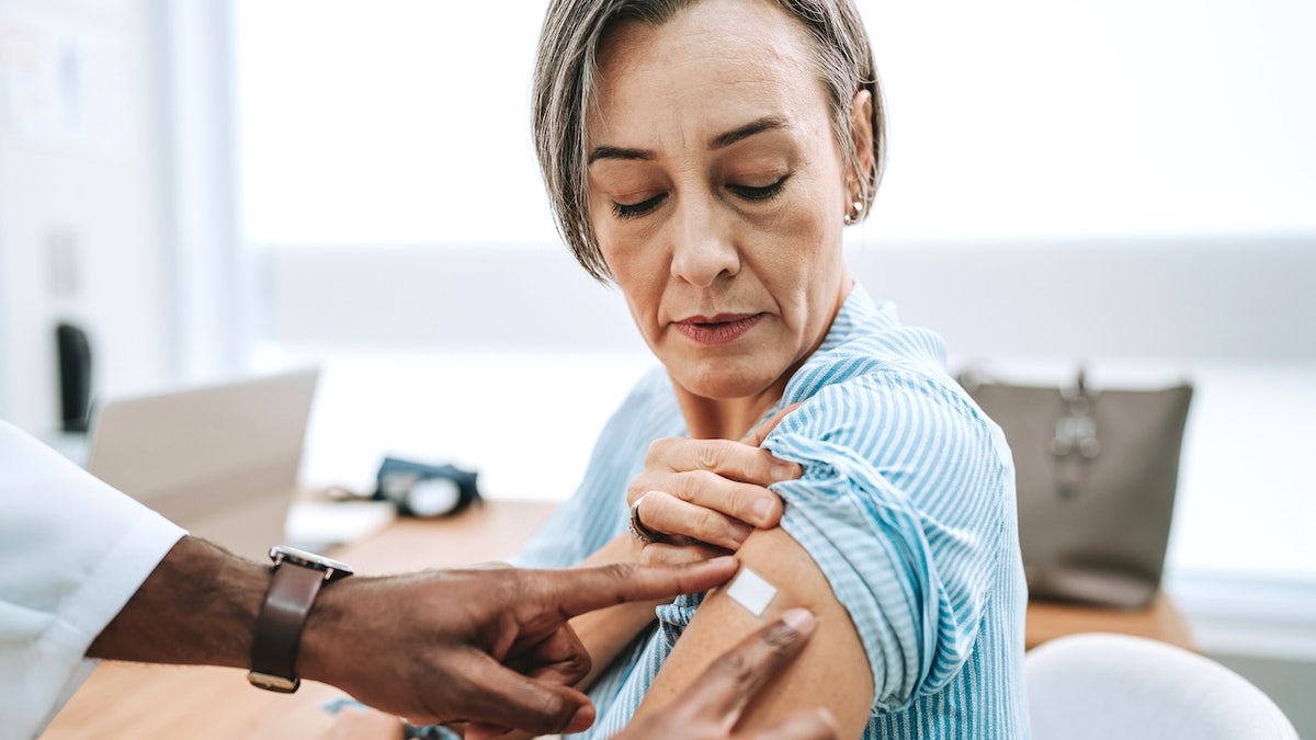 Older woman with bandage on arm after receiving vaccine in hospital