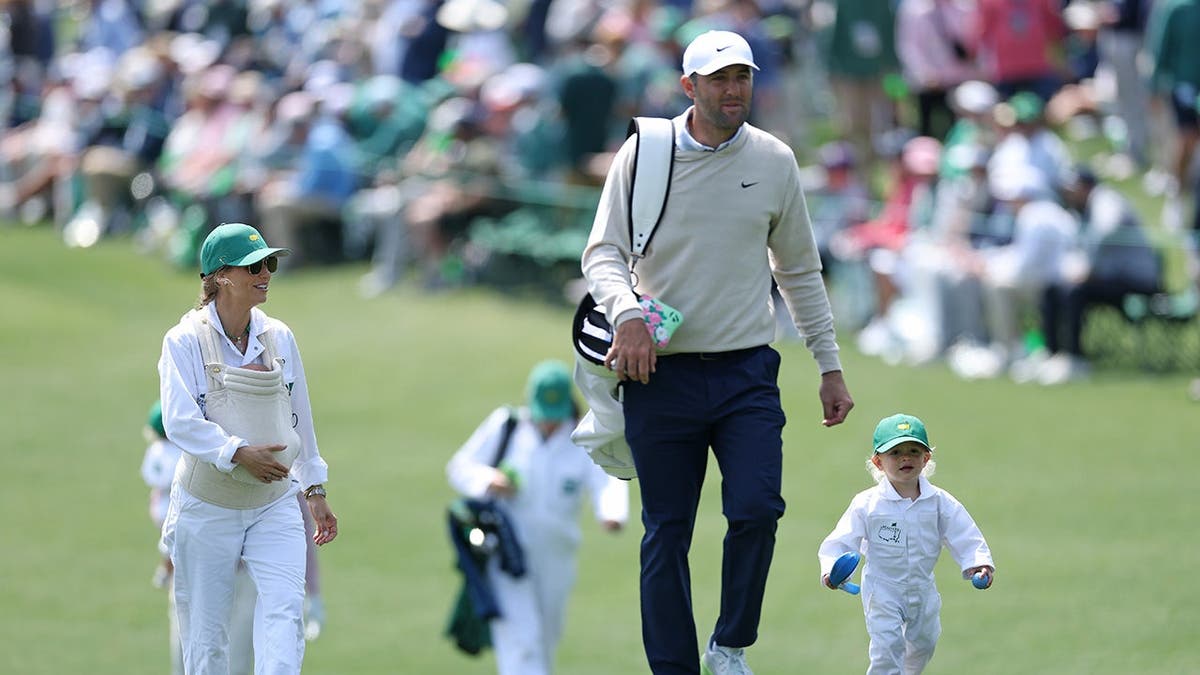 Scottie Scheffler walking with his son Bennett and wife Meredith holding baby Remy at Augusta National Golf Club