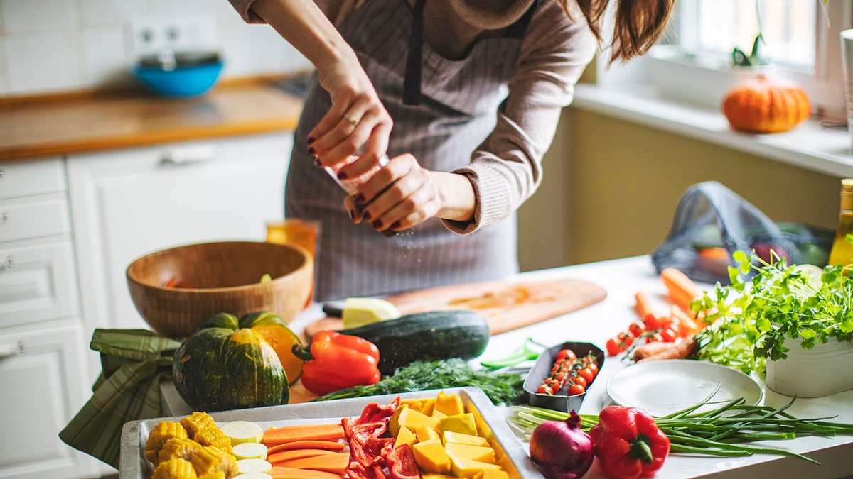 Woman seasoning fresh vegetables.