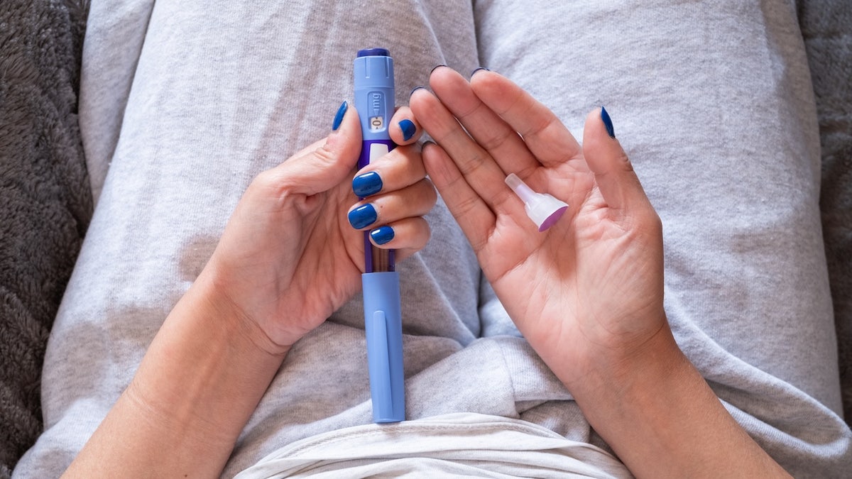 Unrecognizable overweight mature woman holding a syringe of semaglutide medication