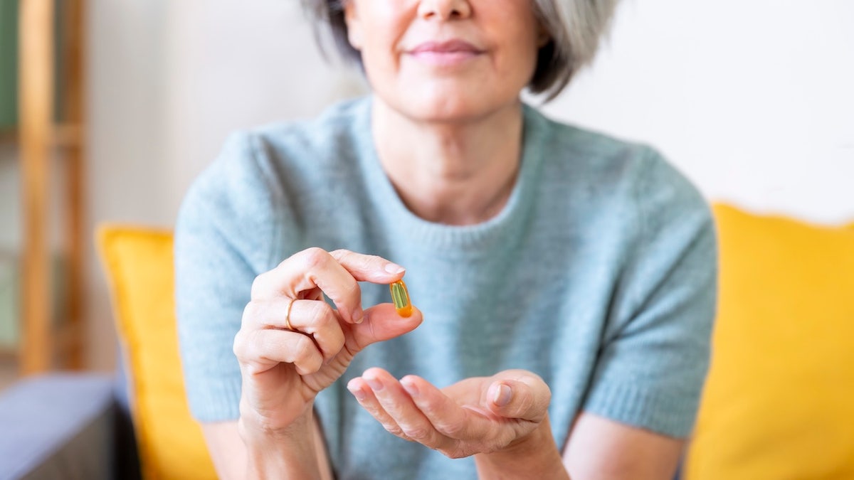 Woman holding omega 3 capsule