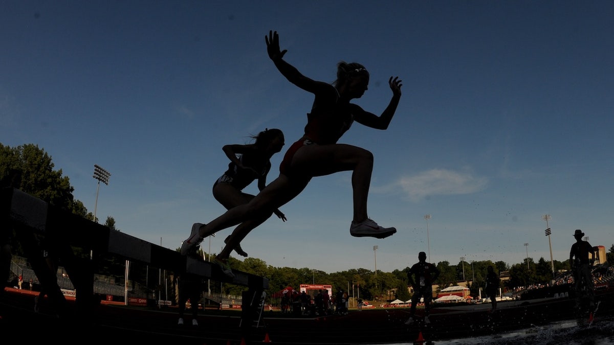 Kira Garry and Madeleine Meyers running over water jump in women's steeplechase race