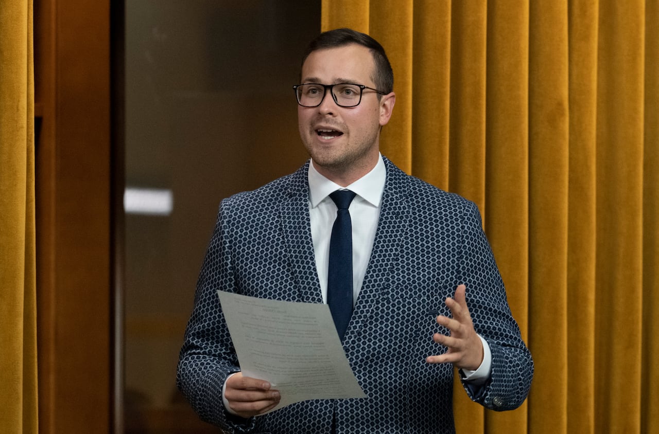 A man holds a pece of paper as he speaks.