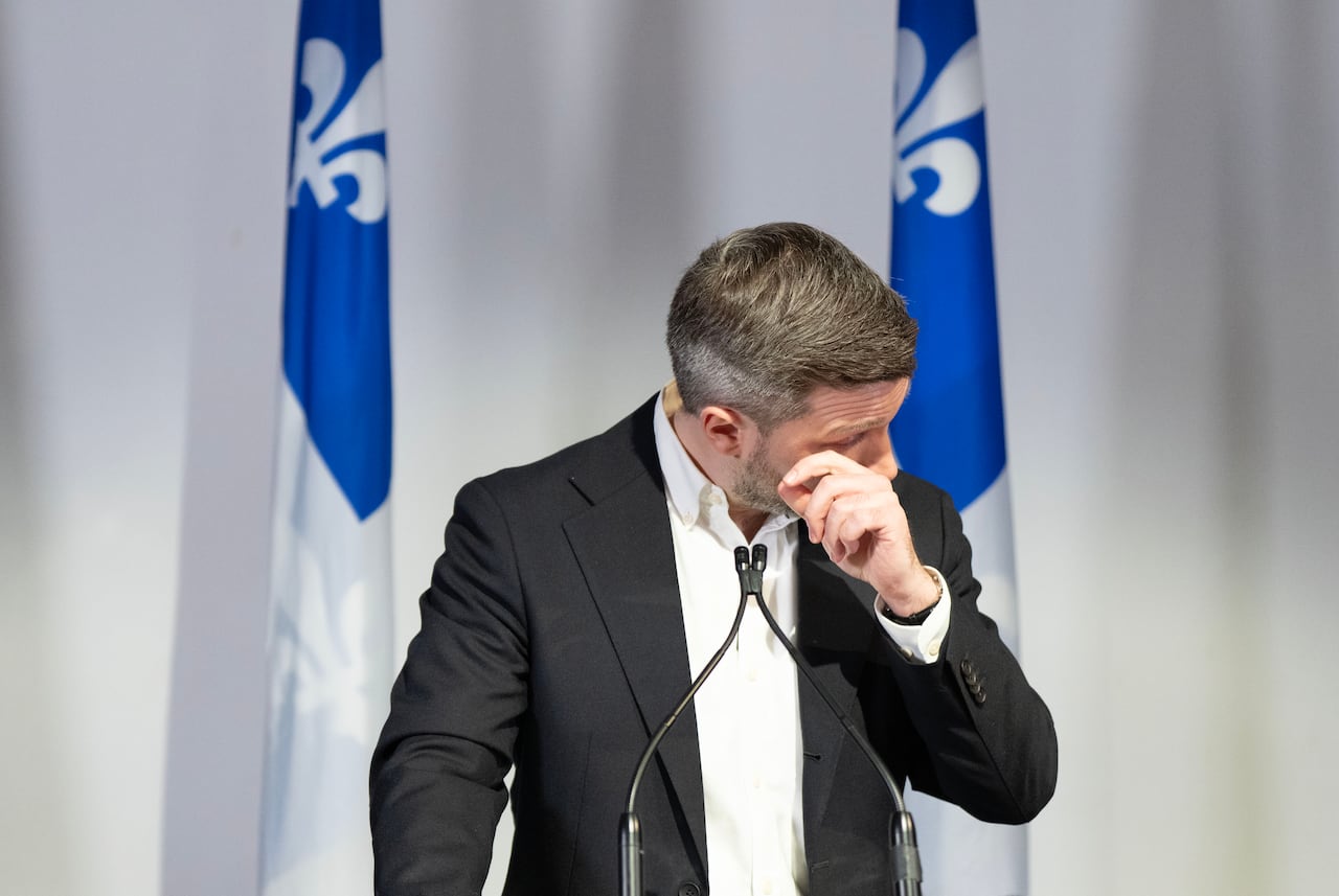 A man in a suit looks emotional as he holds a hand up to his eyes.