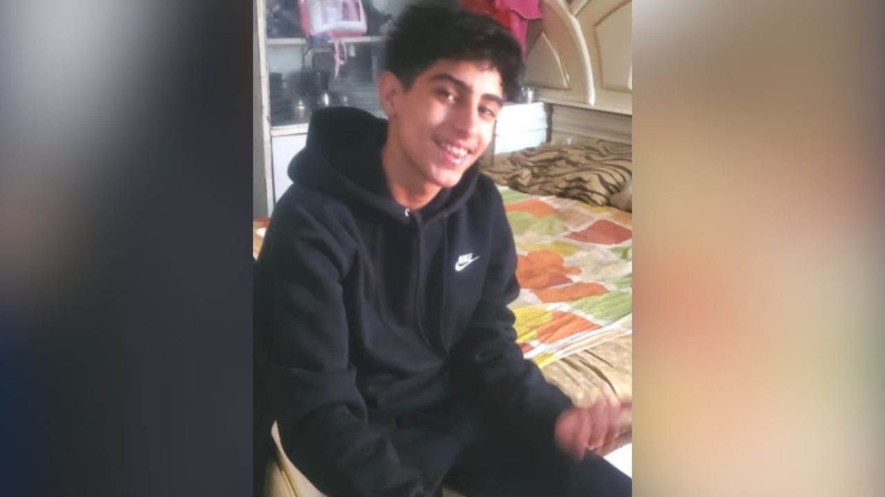 Teenage boy wearing black Nike hoodie, smiling at camera