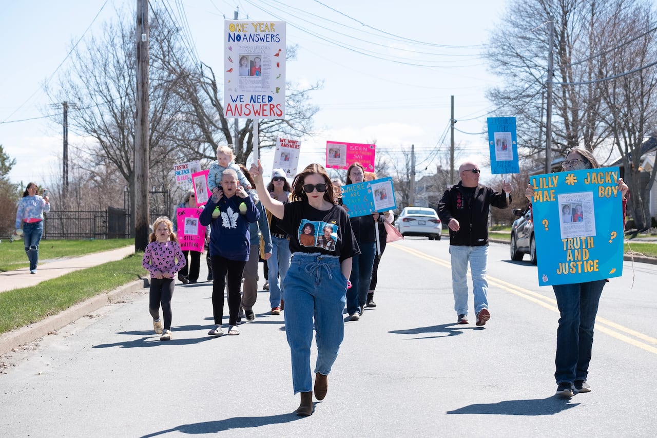 People are shown marching down a street holding signs during a rally.