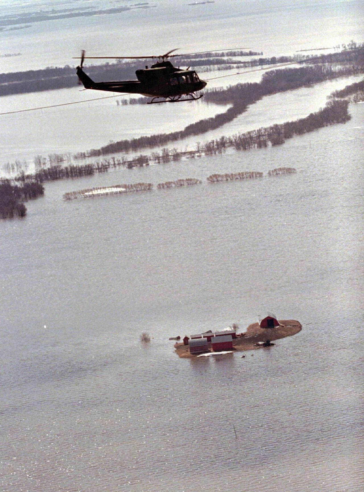 A helicopter flies above flooded land