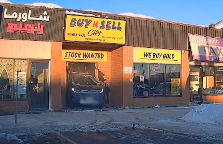 Dash-cam footage of a car damaging the entrance of a store.