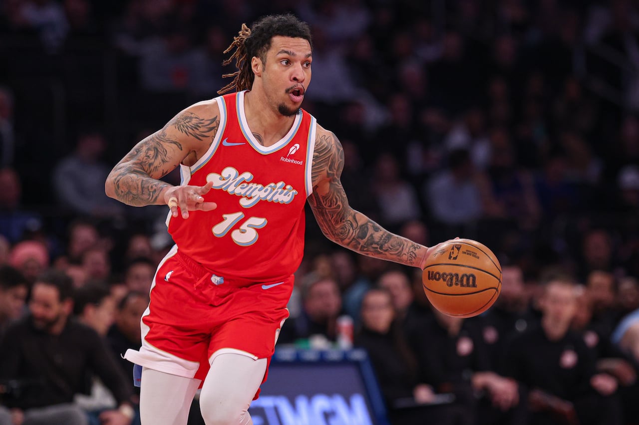 A basketball player in a red uniform dribbles the ball.