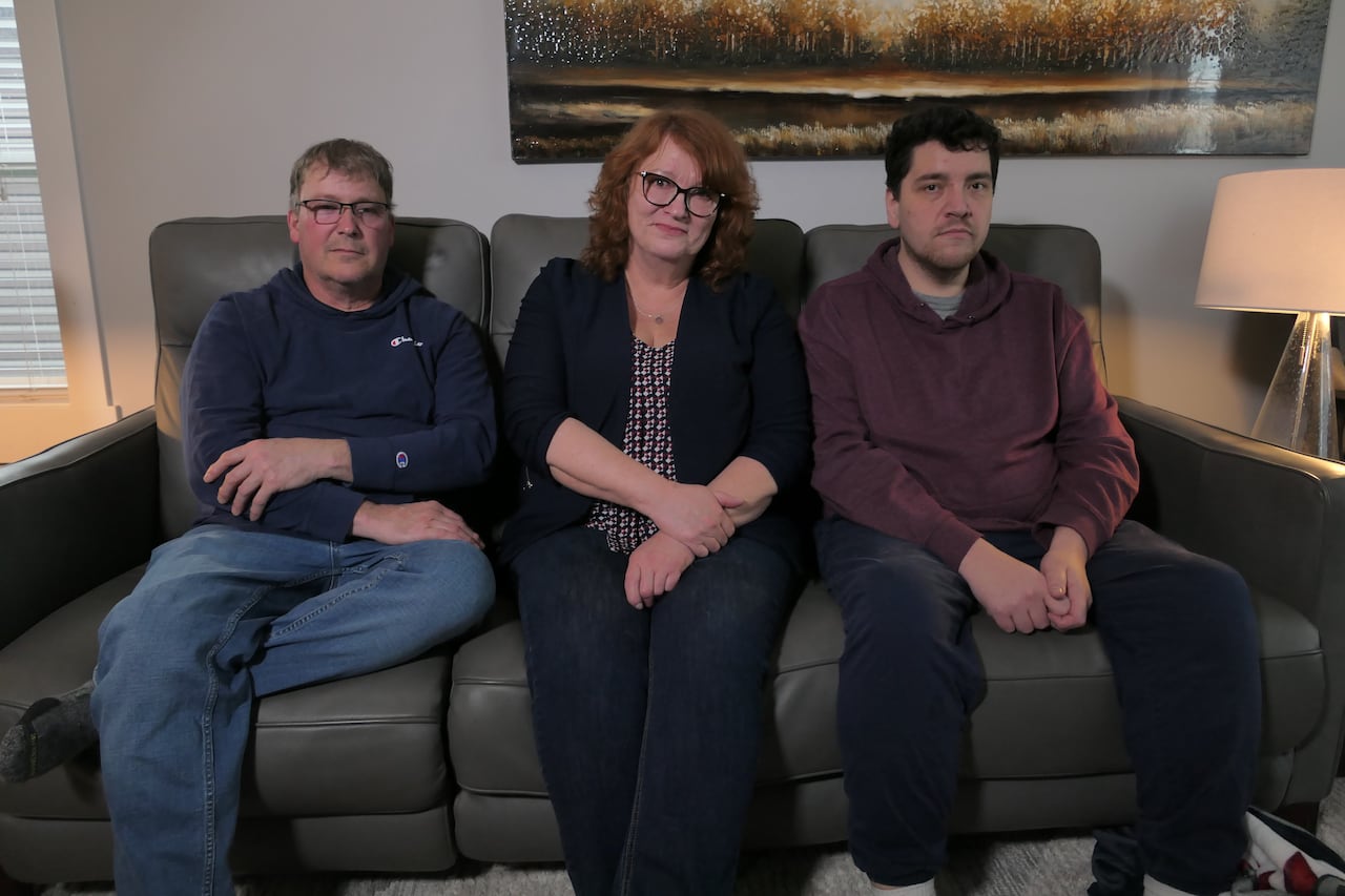 A photo of a man, a woman and their son sitting on a couch.