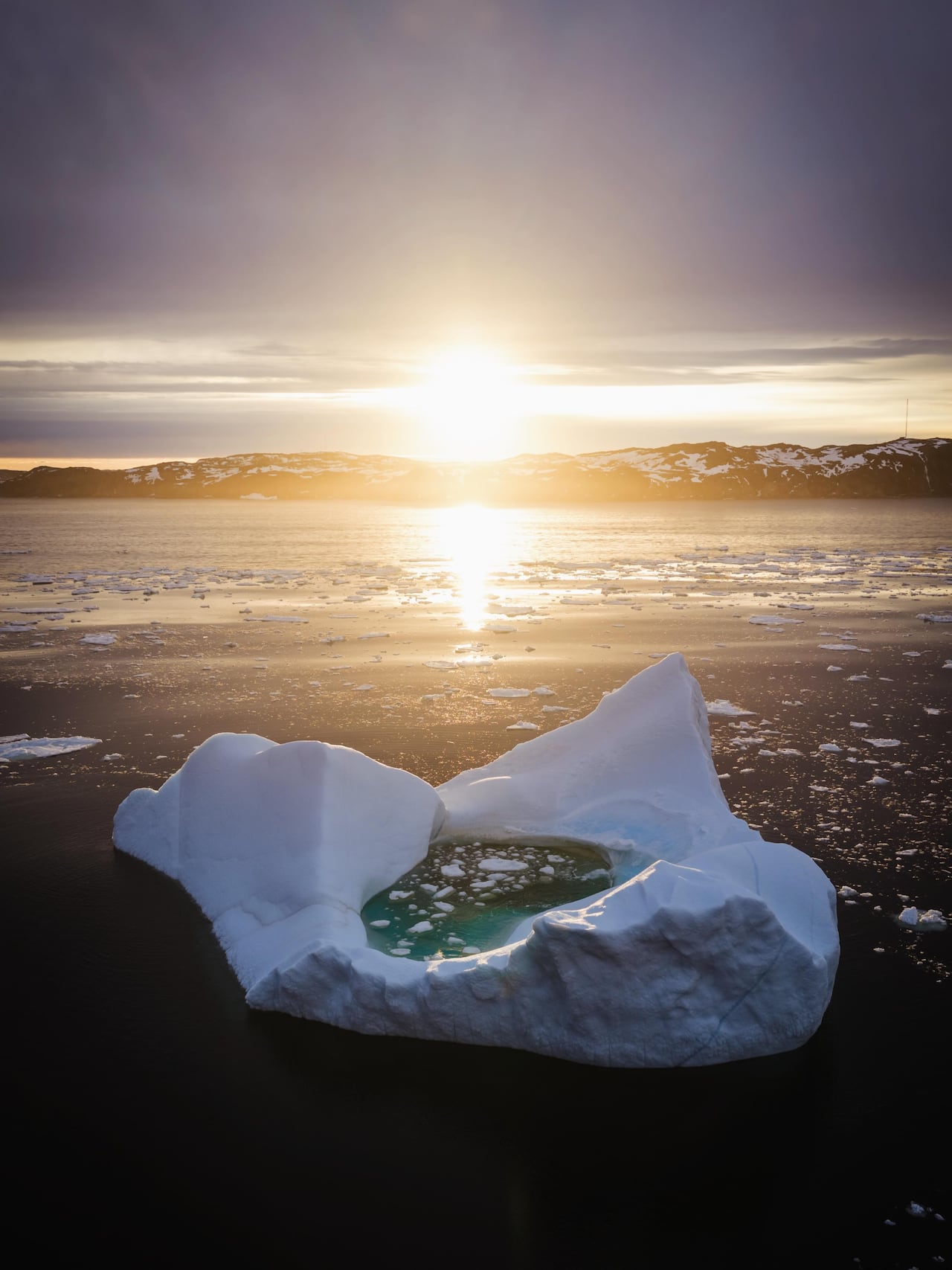 An iceberg in front of a sunset.