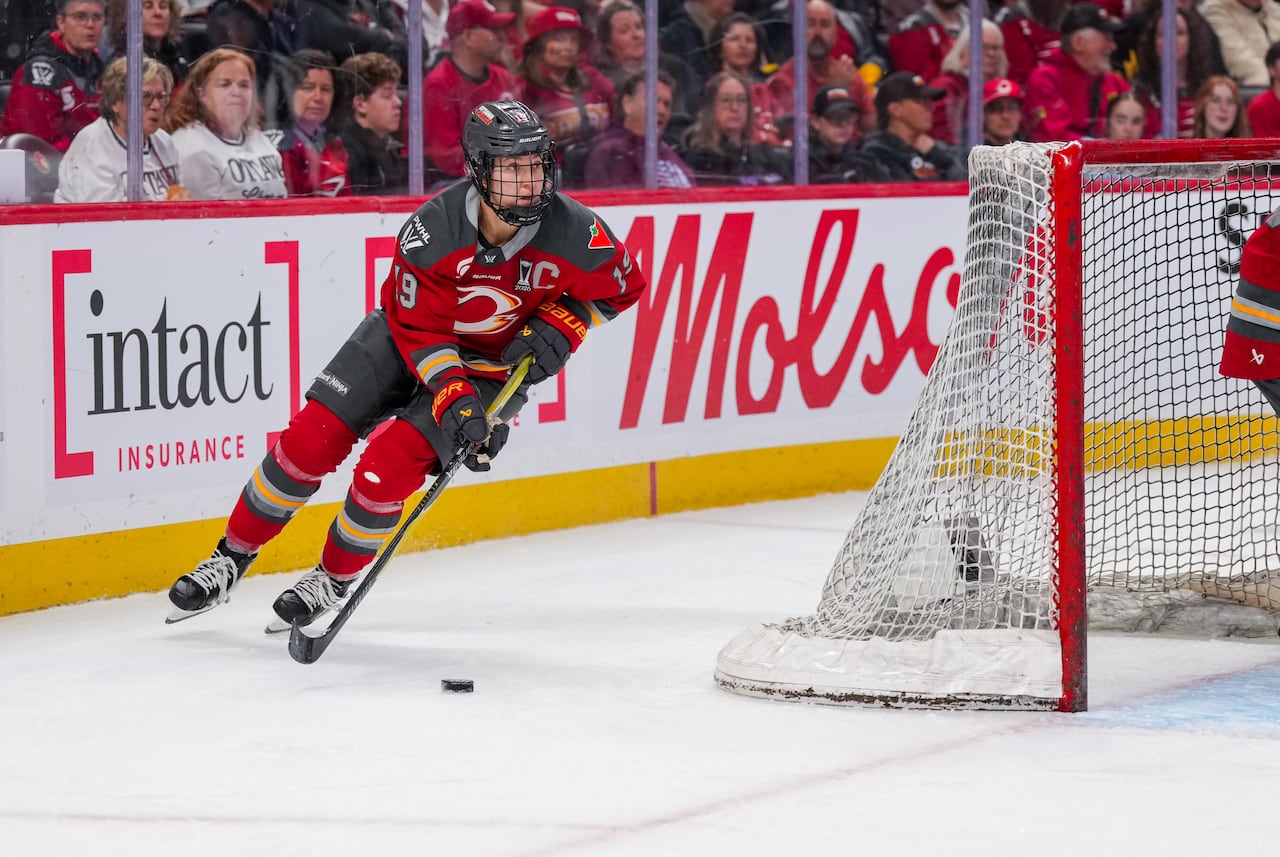 A hockey player skates with the puck.