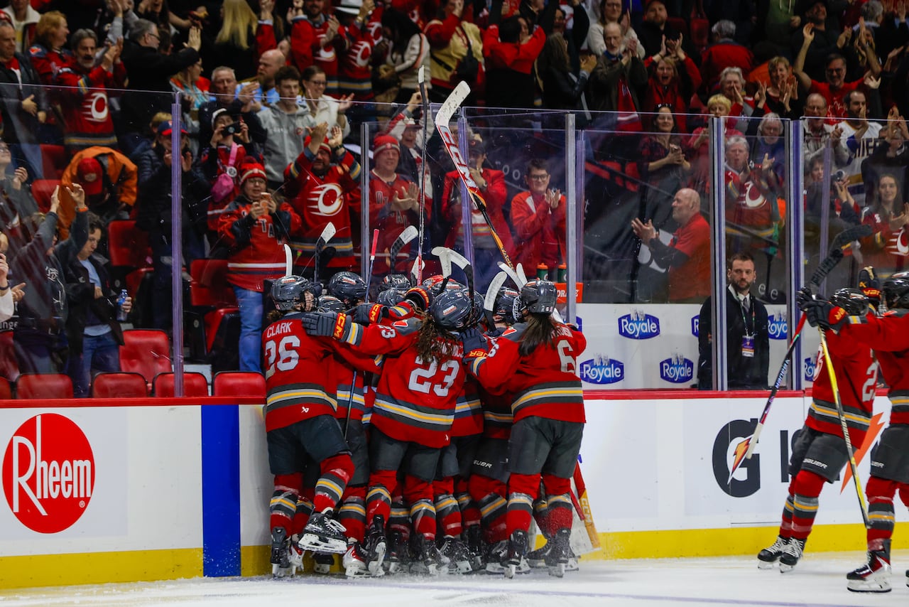 Hockey players celebrate along the boards after winning a game.