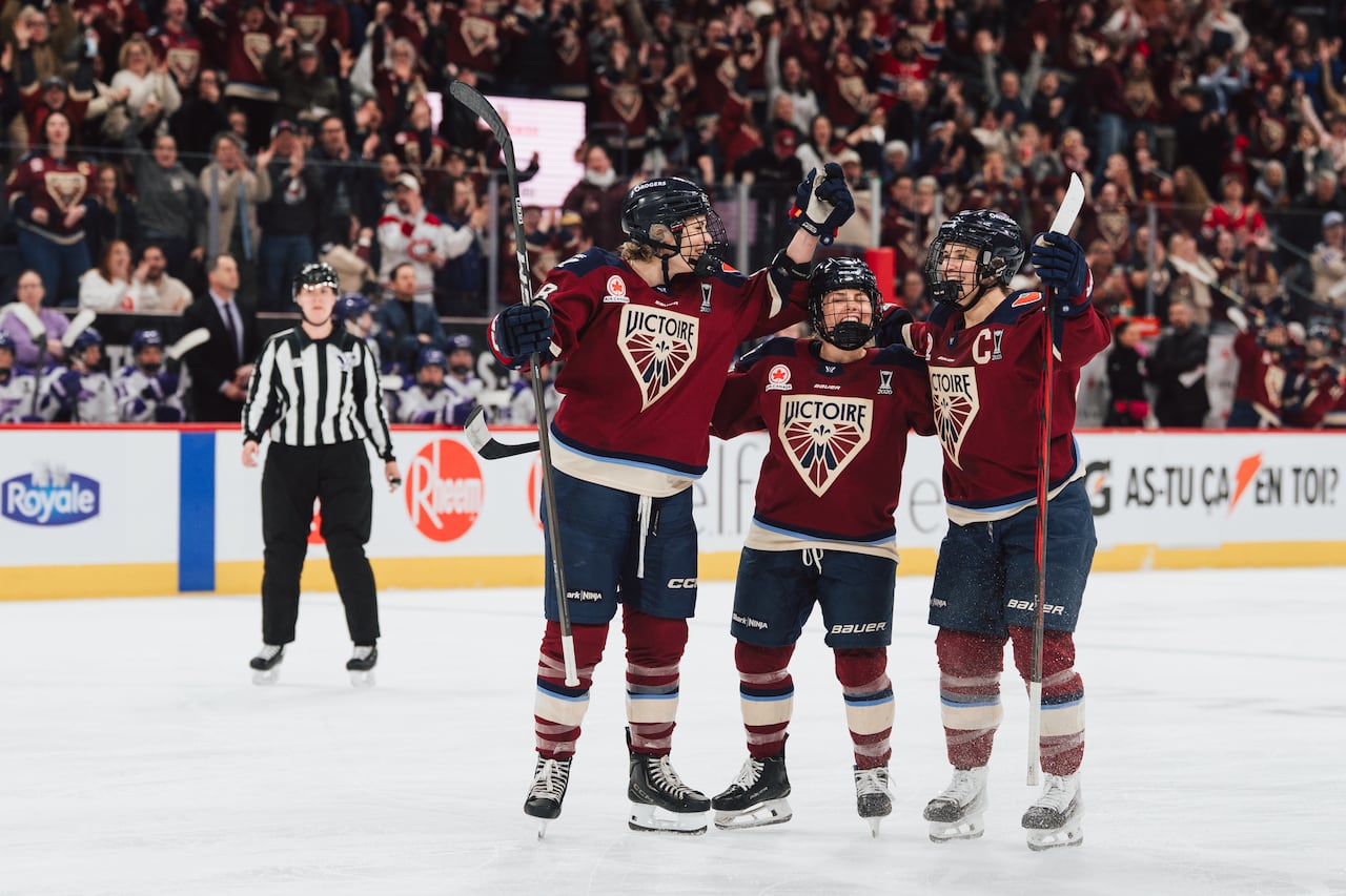 Three hockey teammates celebrate on the ice.