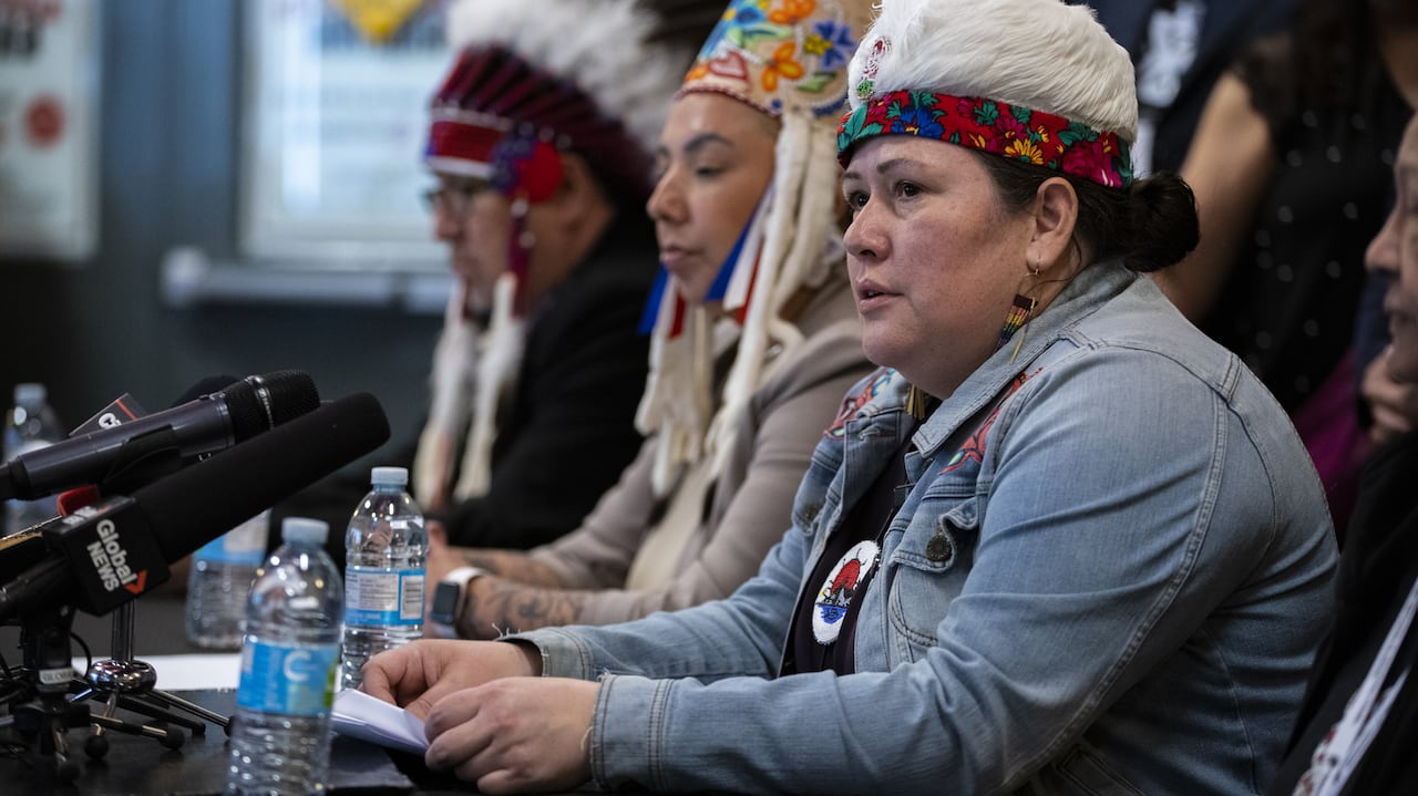 A woman speaking with the other chiefs in the background.