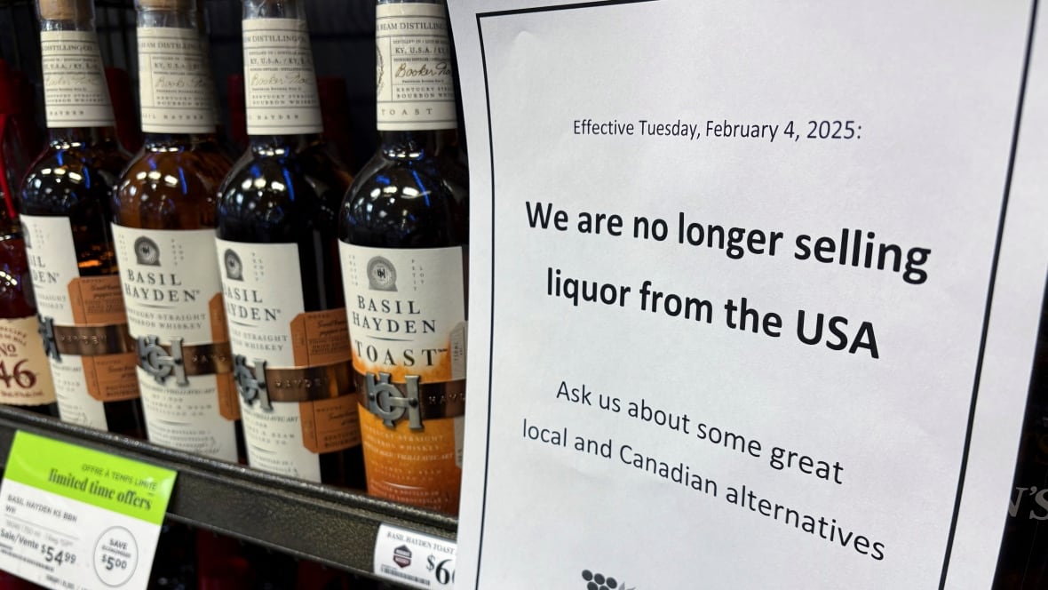A sign in a white piece of paper is besides a group of bottles of wine.