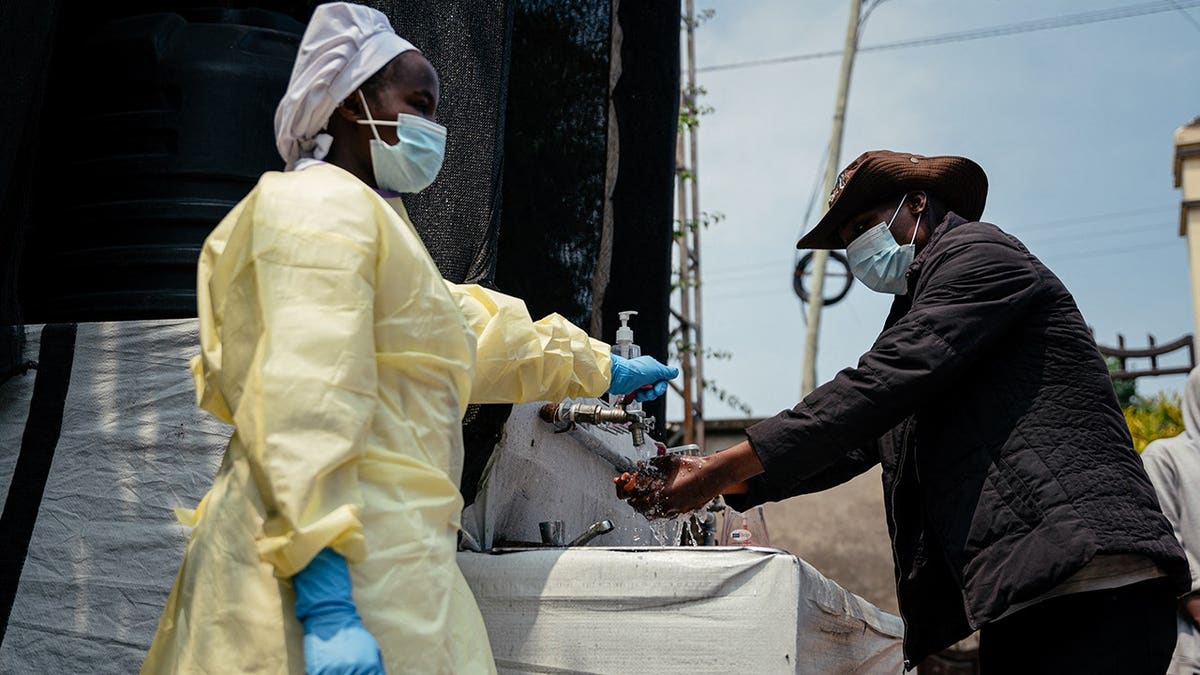 A visitor washes his hands at a checkpoint outside Kyeshero Hospital in Goma