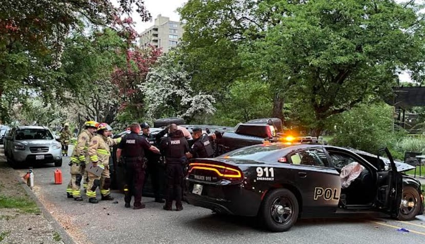 Police and firefighters gather near a police vehicle that appears to have been in a crash.