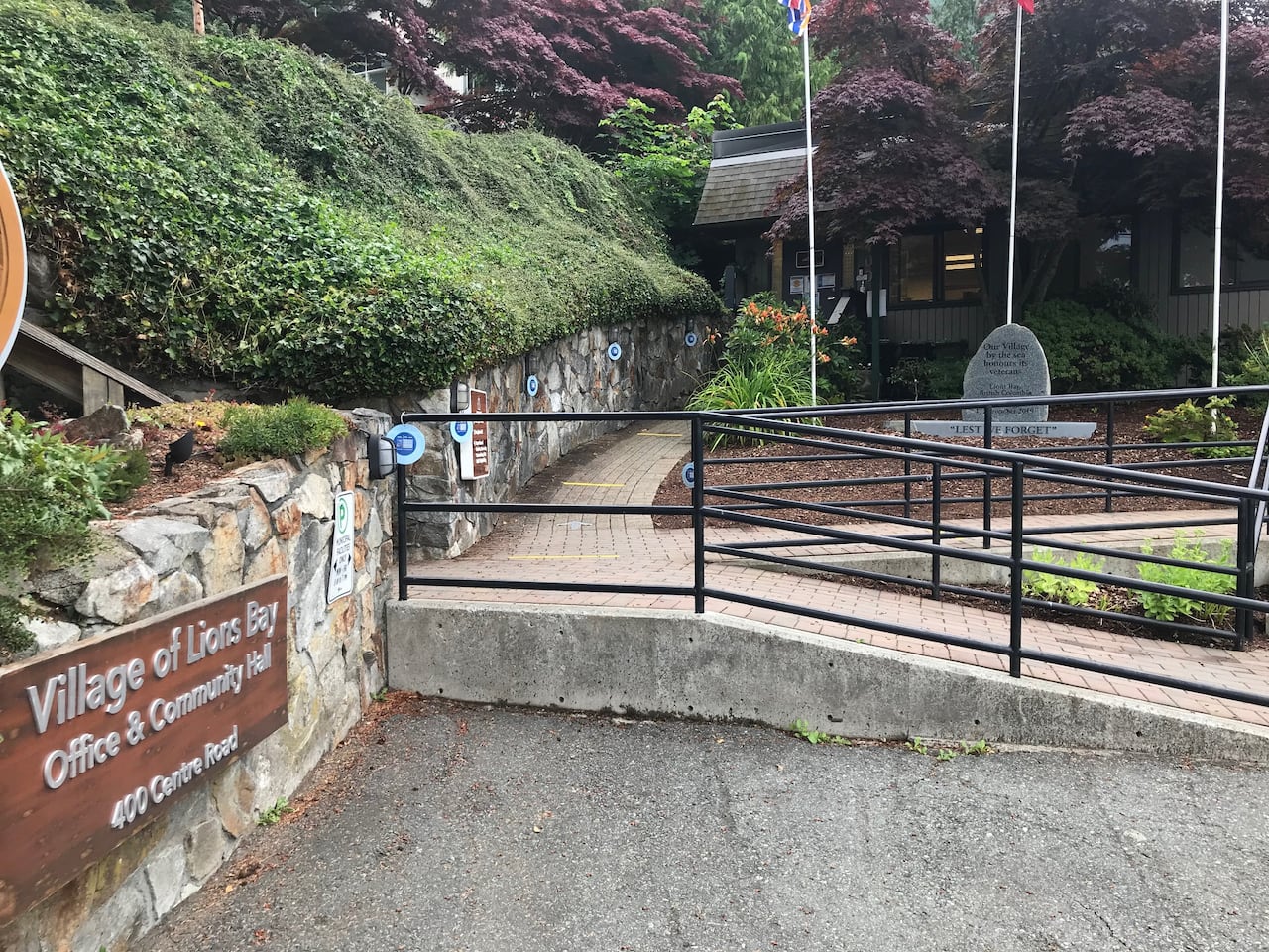 A ramp is seen, with a sign reading 'Village of Lions Bay Office and Community Hall' on the left.