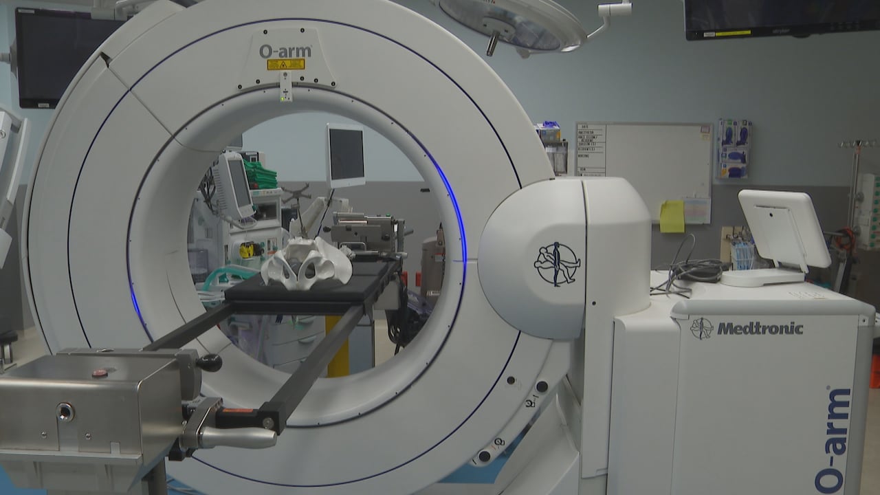 An empty operating room features a circular machine with a bed in the middle and a mock spine set up for demonstrations.