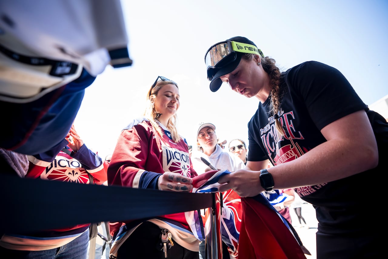 A female hockey players signs fans' authographs.