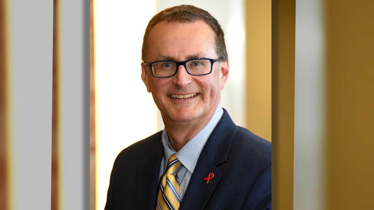 A man in a suit, smiling.