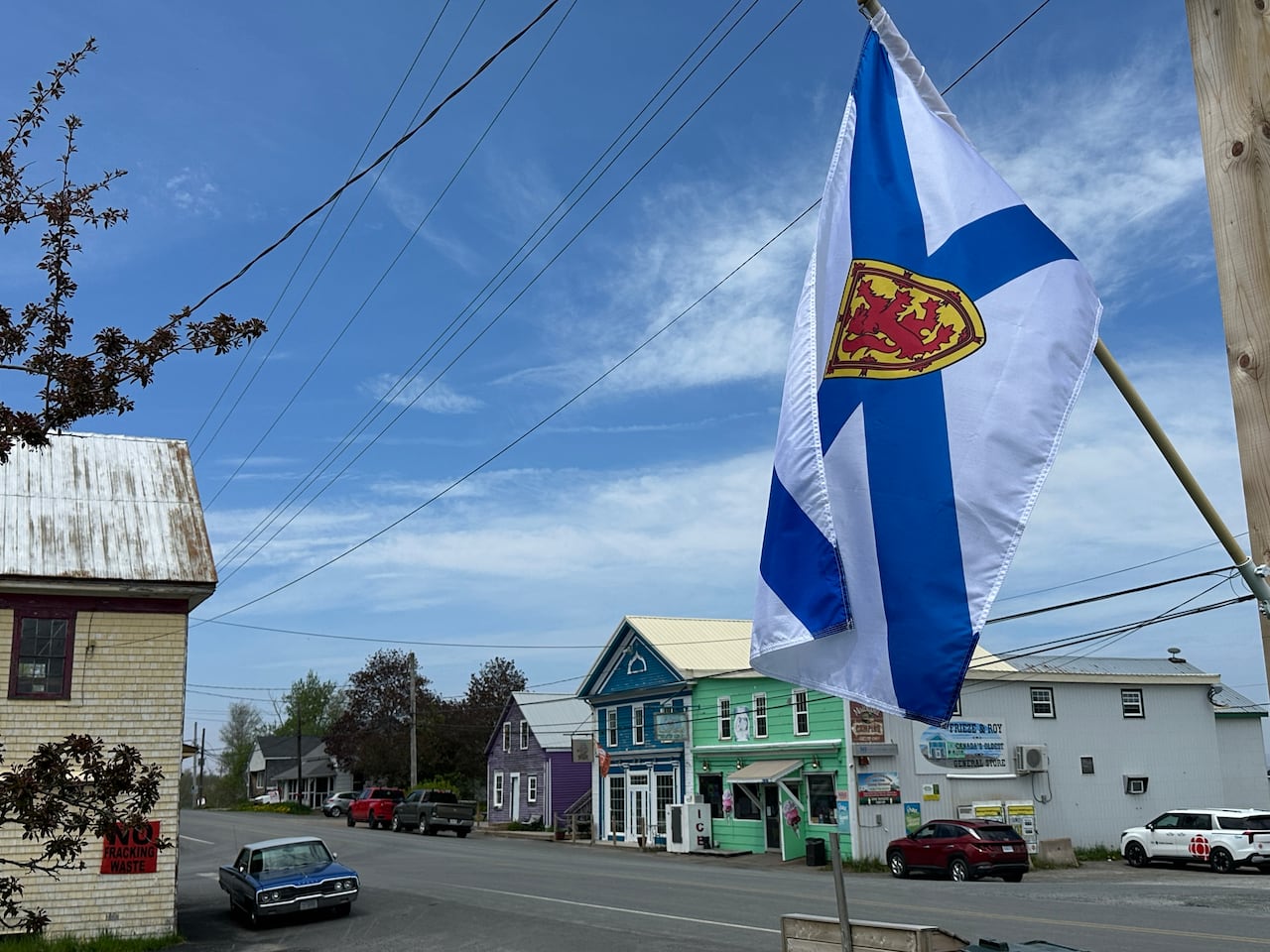 A Nova Scotia flag hangs in front of a quiet street with colourful homes.