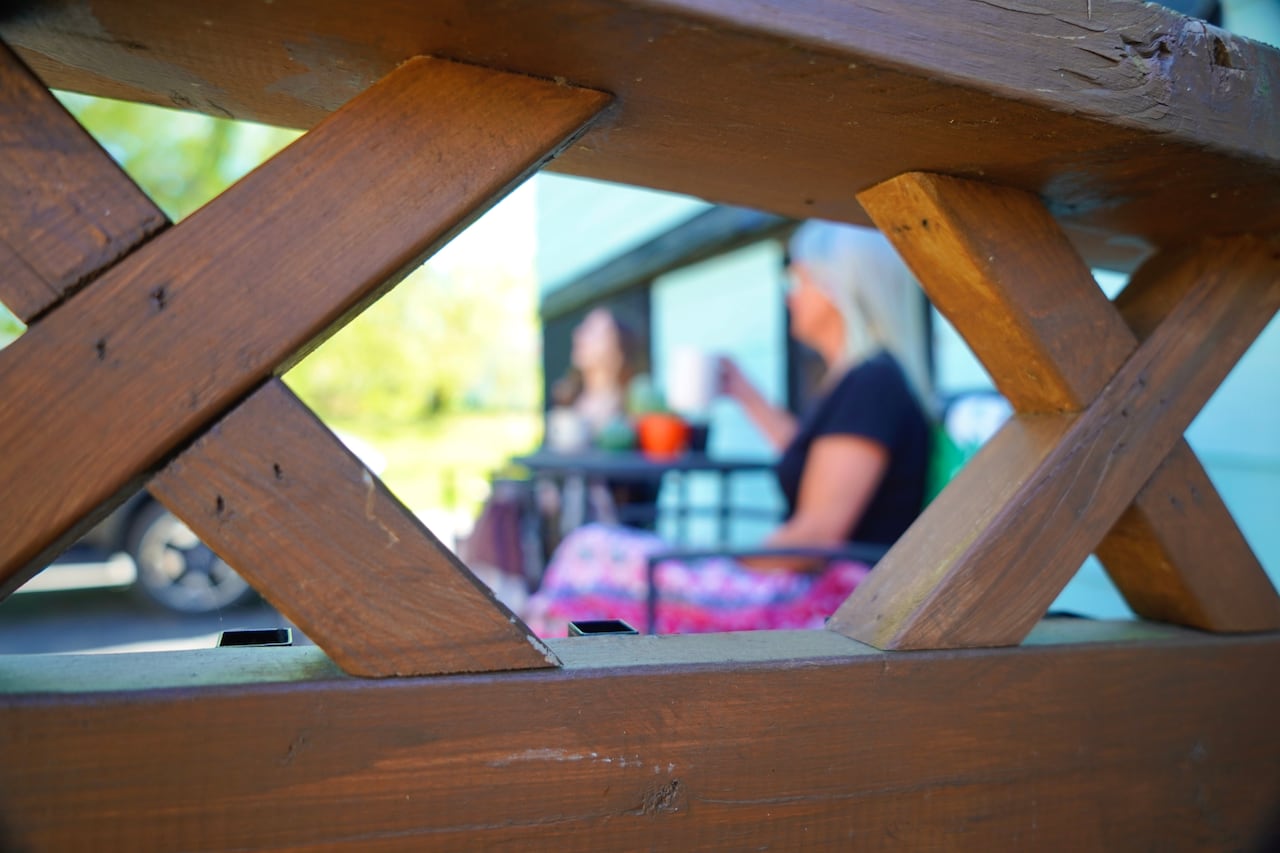 A woman talks to another person on a deck, their identities obscured.