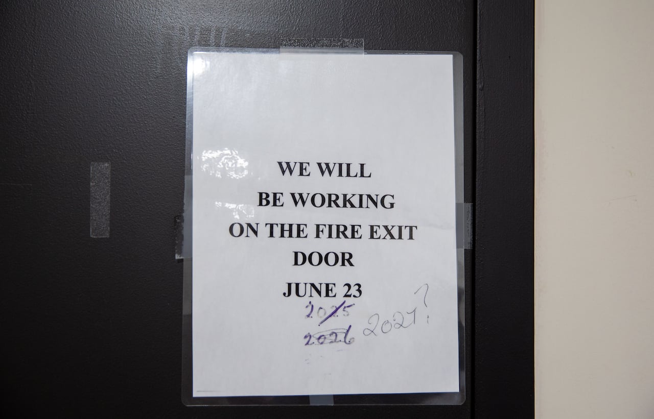 A close-up of a sign on a door that says 'we will be working on the fire exit door June 23.'