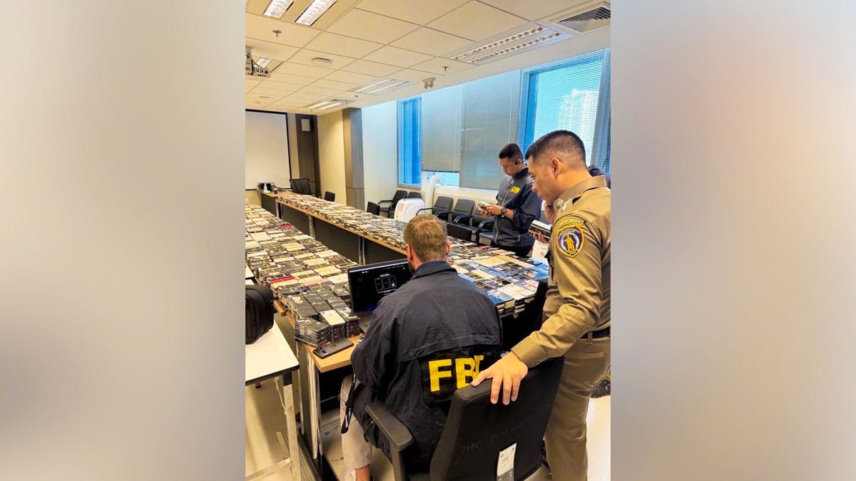 FBI agents sit in front of devices seized in anti-scam operations