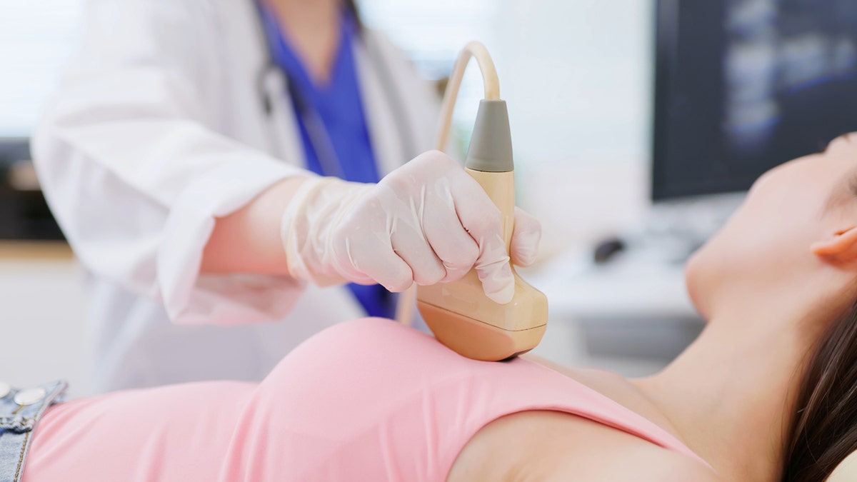 Woman receiving breast ultrasound examination in medical setting