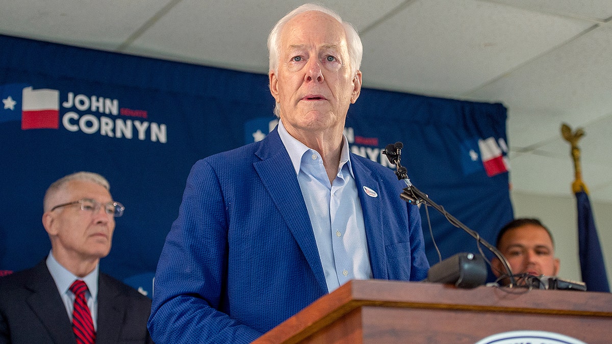 Sen. John Cornyn speaking at a podium at a campaign event in Austin, Texas