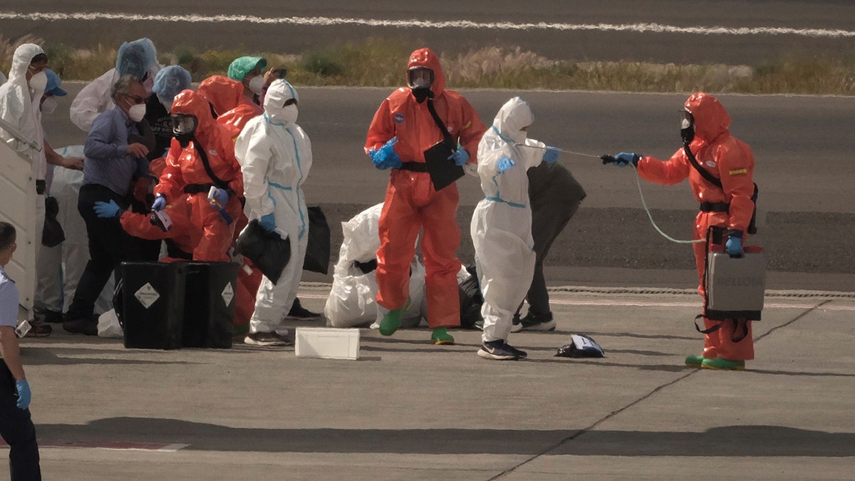 Spanish government officials spraying disinfectant on passengers at Tenerife airport