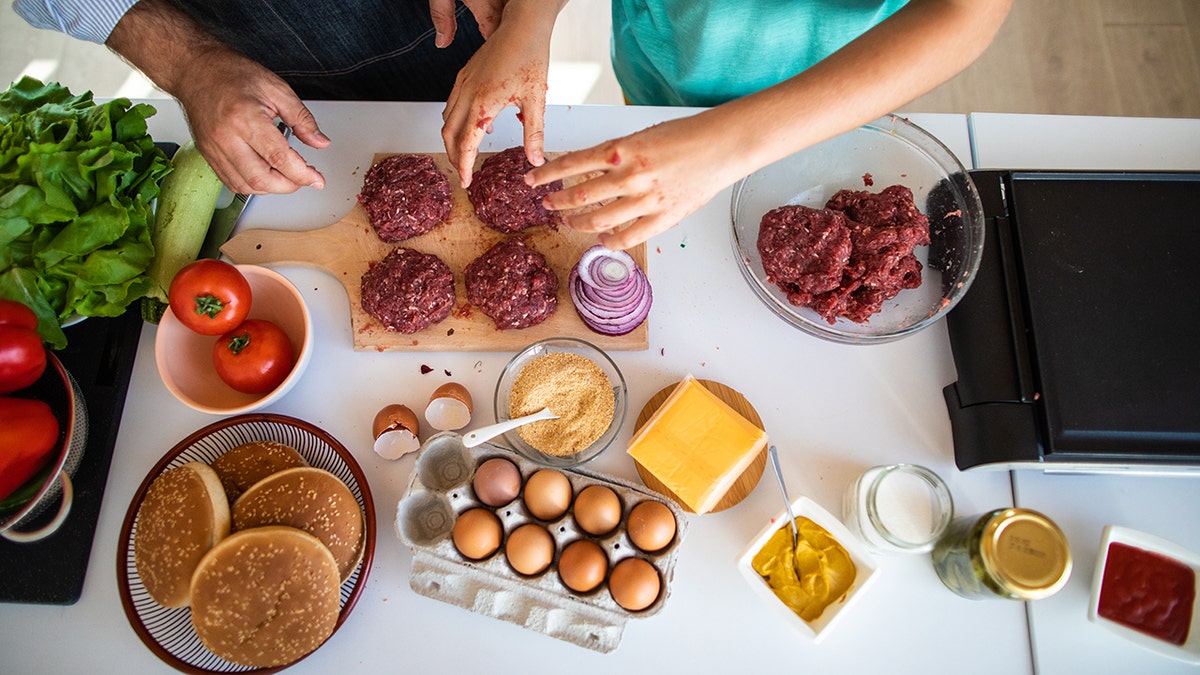 Father and son preparing cheeseburger ingredients in kitchen