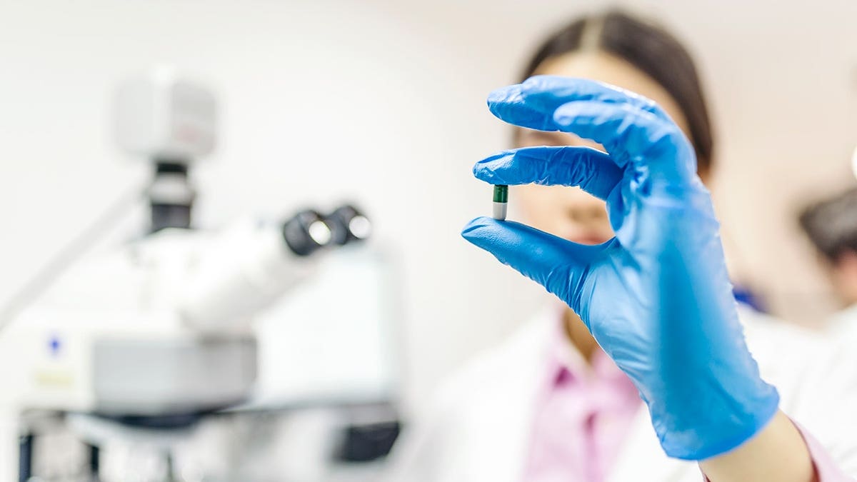Young female scientist holding a pill in a laboratory setting