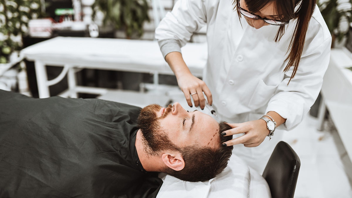 Male patient receiving dermal fillers in forehead from doctor