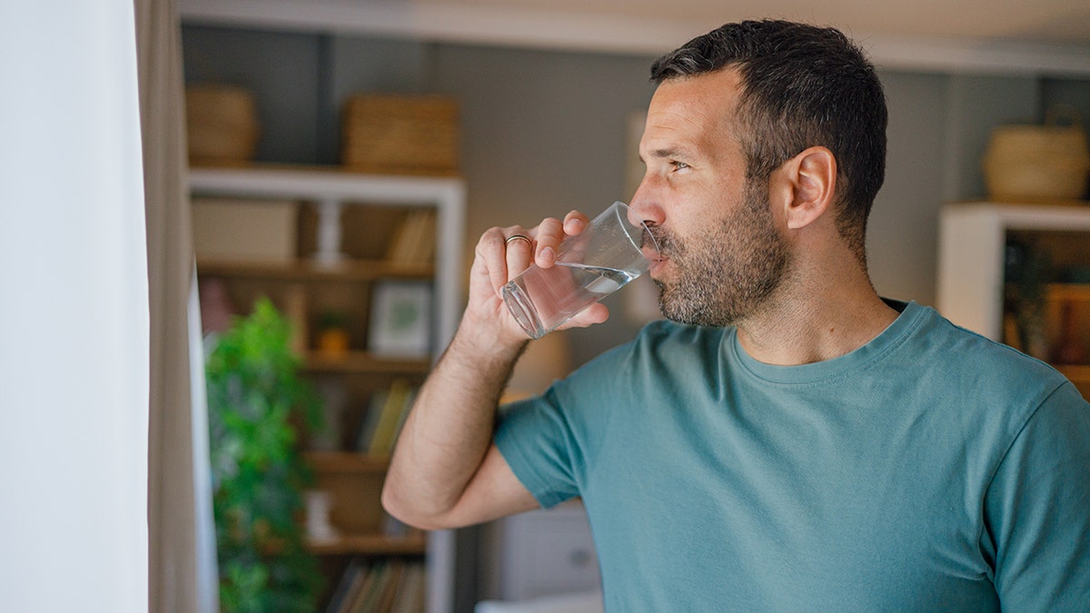 Man drinking a glass of water indoors