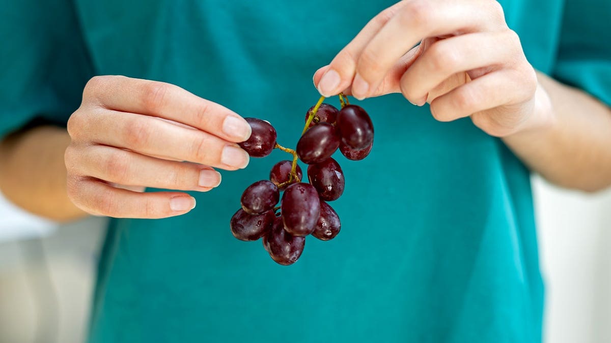 Hands holding fresh red grapes close up
