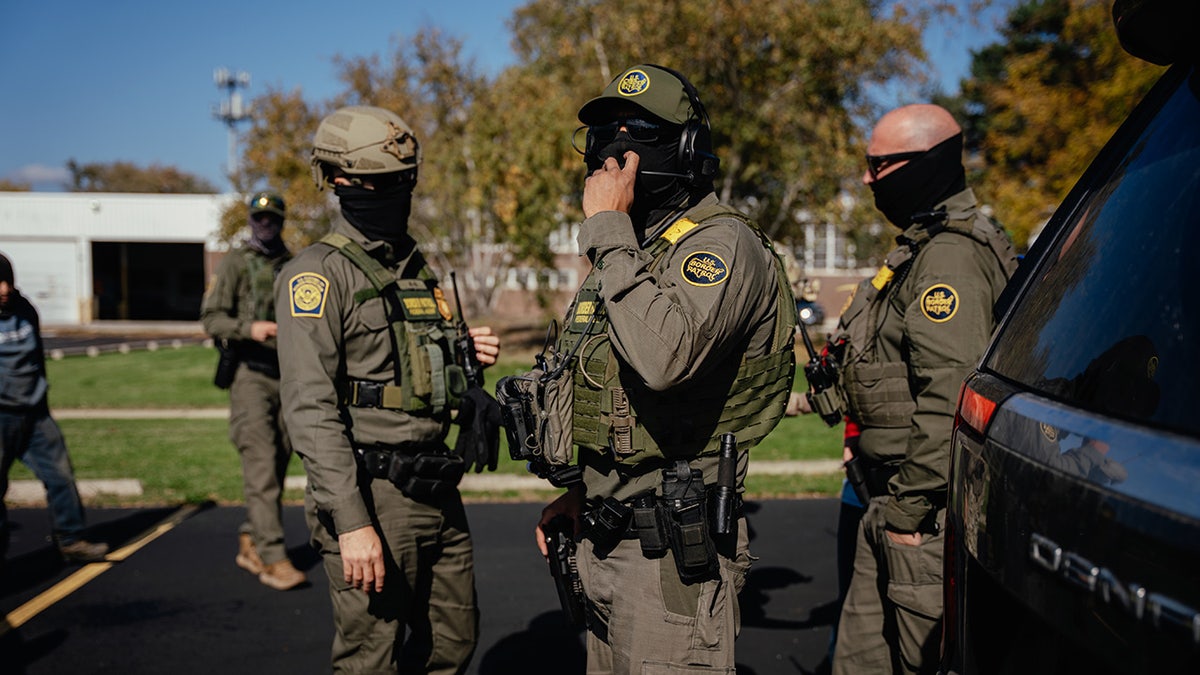 Federal agents standing near unmarked cars in a Chicago neighborhood