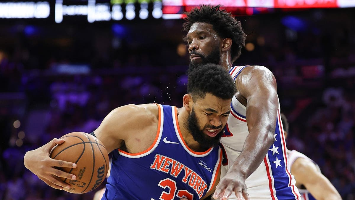 Karl-Anthony Towns driving against Joel Embiid during NBA playoff game