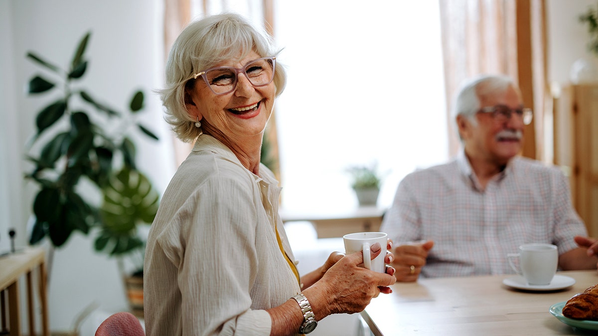 Senior woman sitting at a table posing for the camera at home