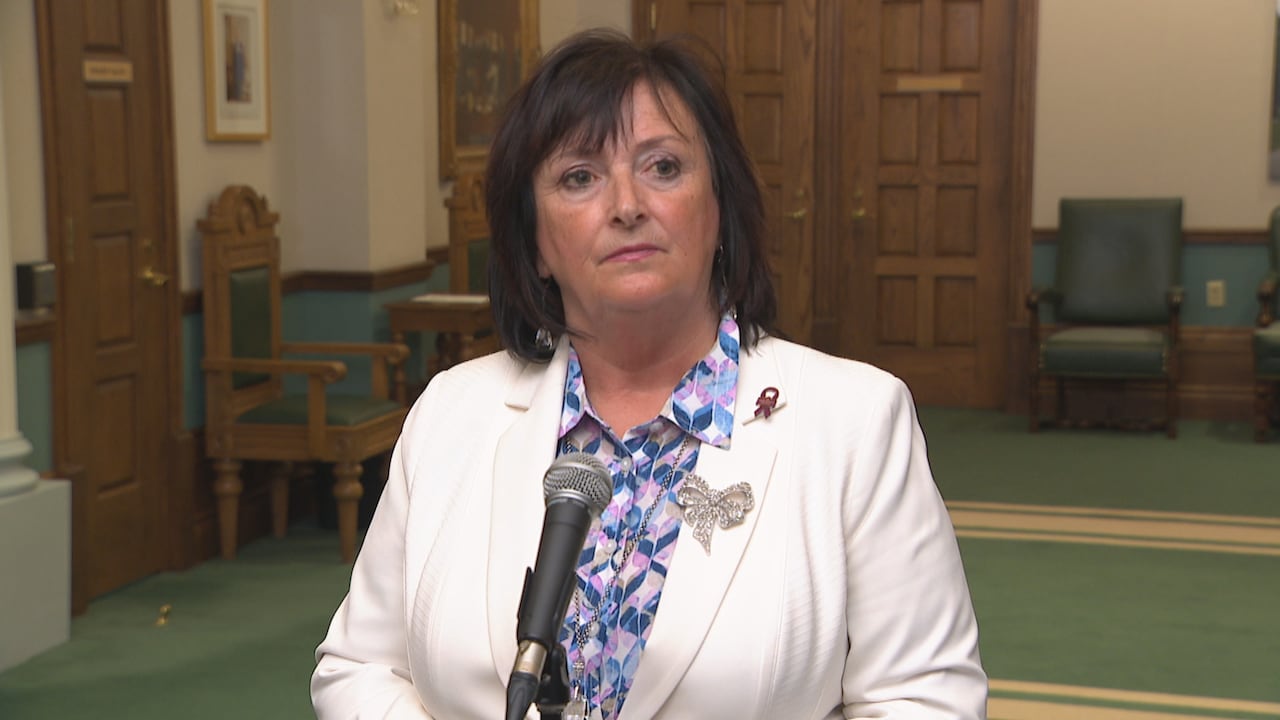 A woman wearing a white coat in front of a microphone.