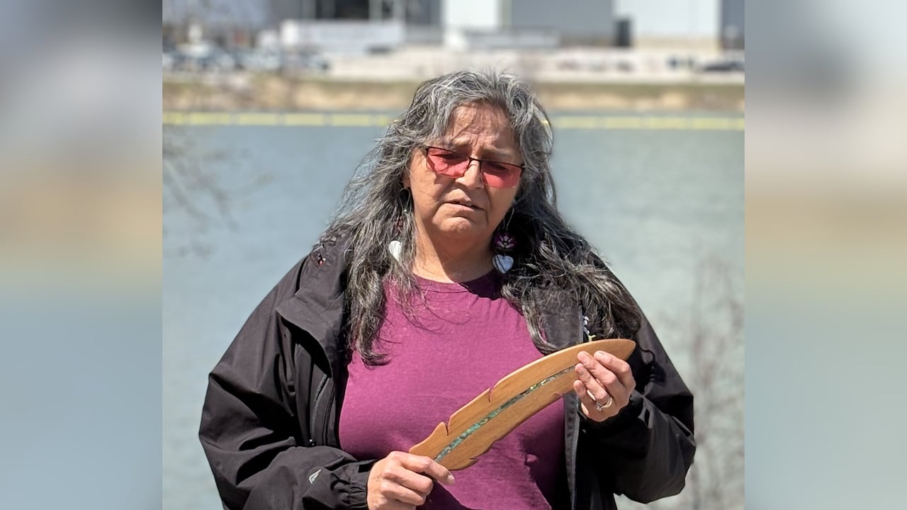 A person is seen holding a wooden feather outside.
