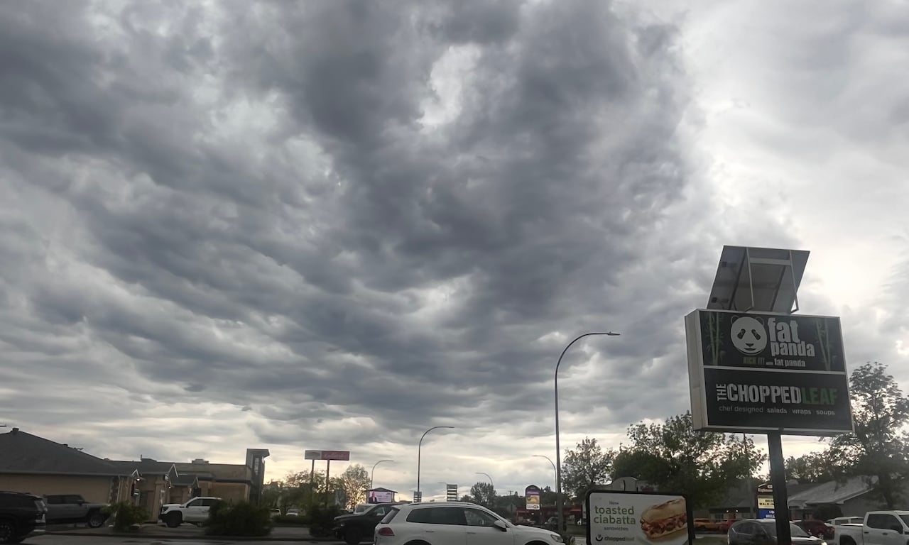 Grey and white clouds threaten in the sky above a city street.