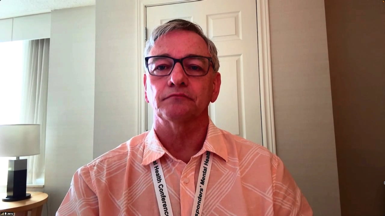 A man sits in a hotel room on a Zoom call.