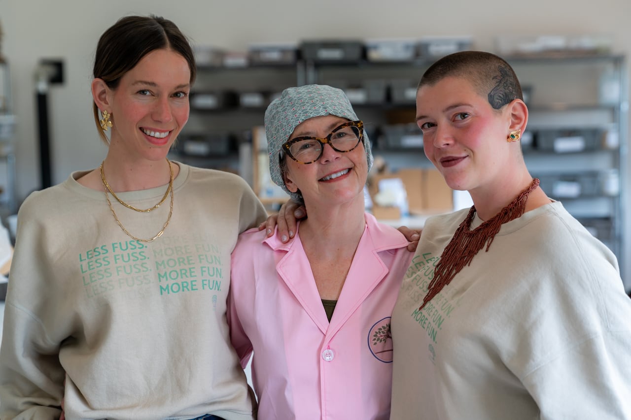 Three women smile and pose for a photo
