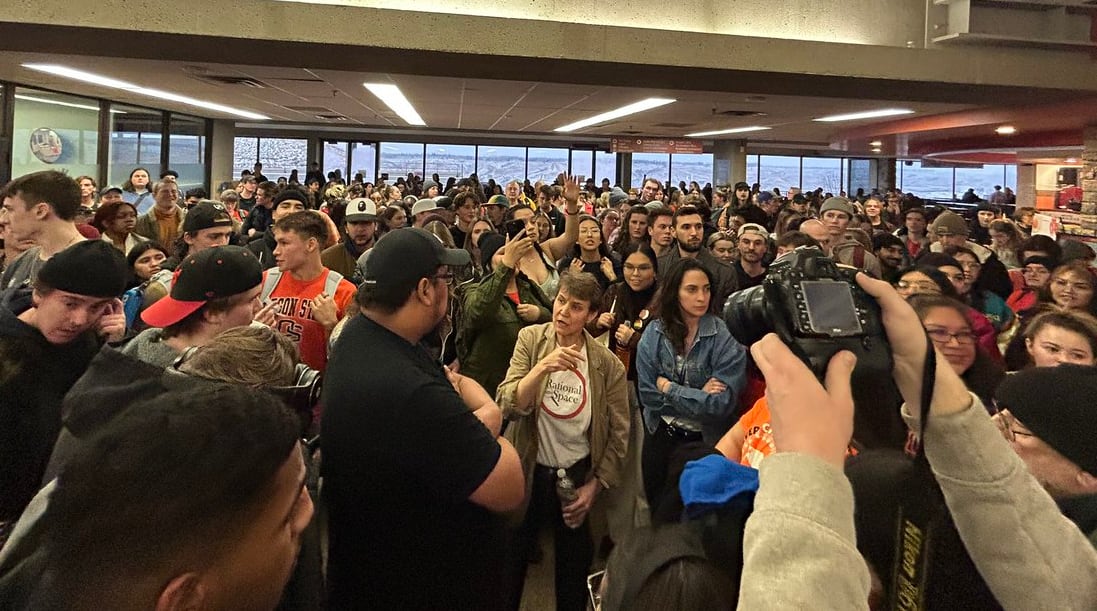 A large crowd of people is pictured in an atrium.