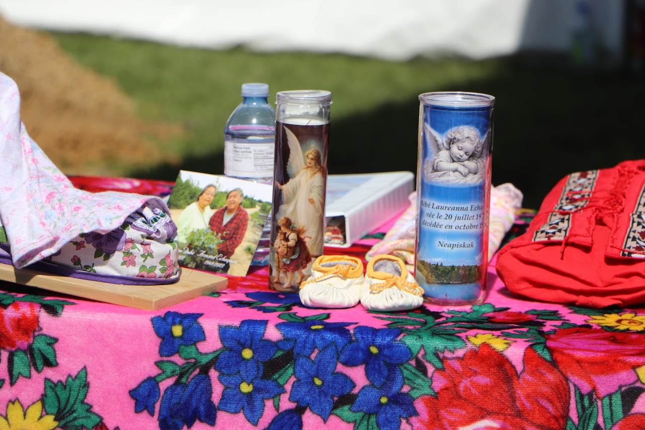 Baby shoes and a candle were laid on a table in front of the exhumation site.