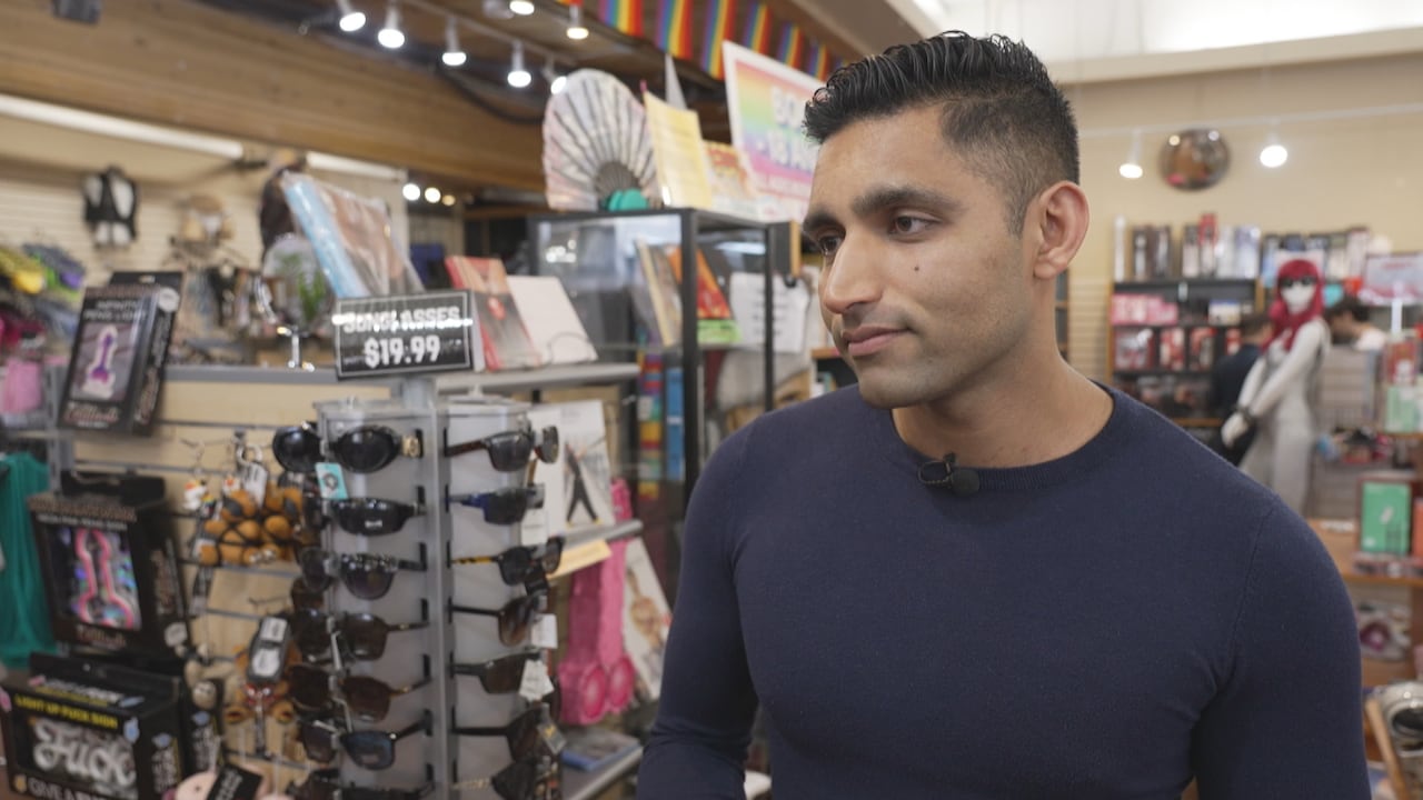 A man in a blue sweater stands in a store.